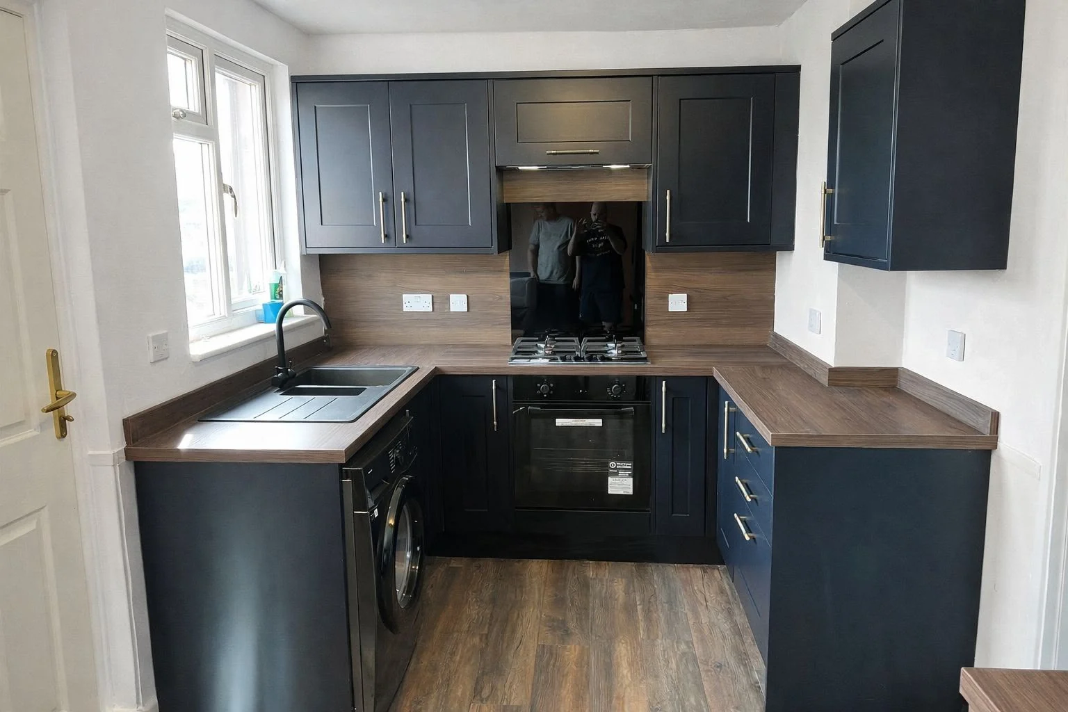Completed kitchen with dark shaker-style cabinets, timber-effect worktops and coordinated flooring