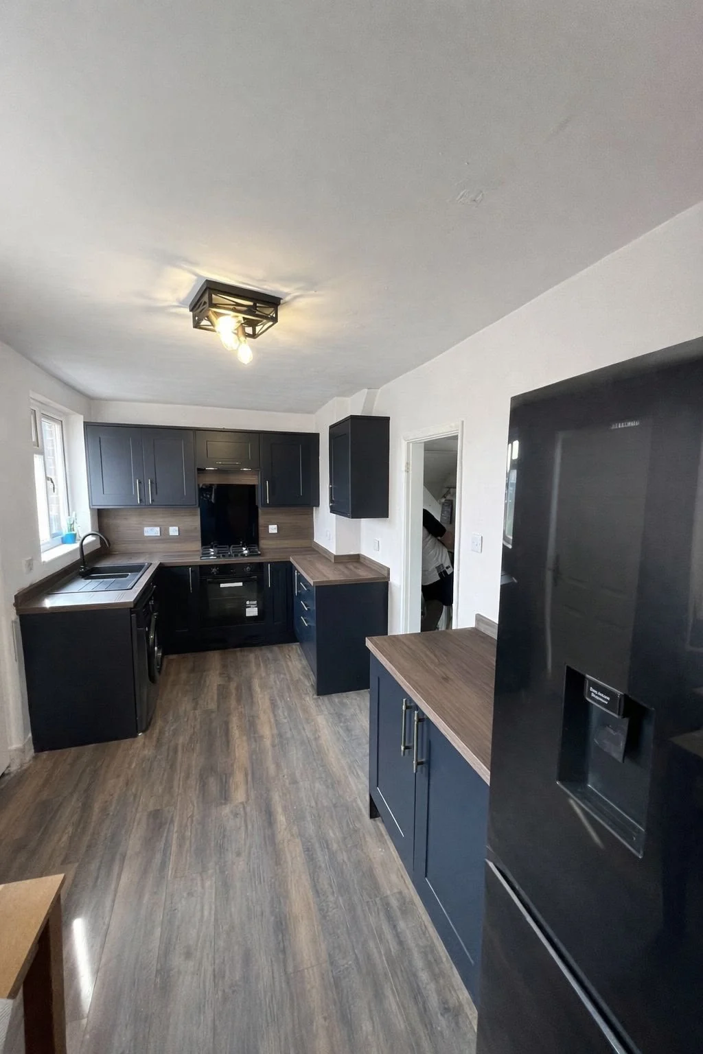 Completed kitchen installation with dark cabinets and timber-effect worktops